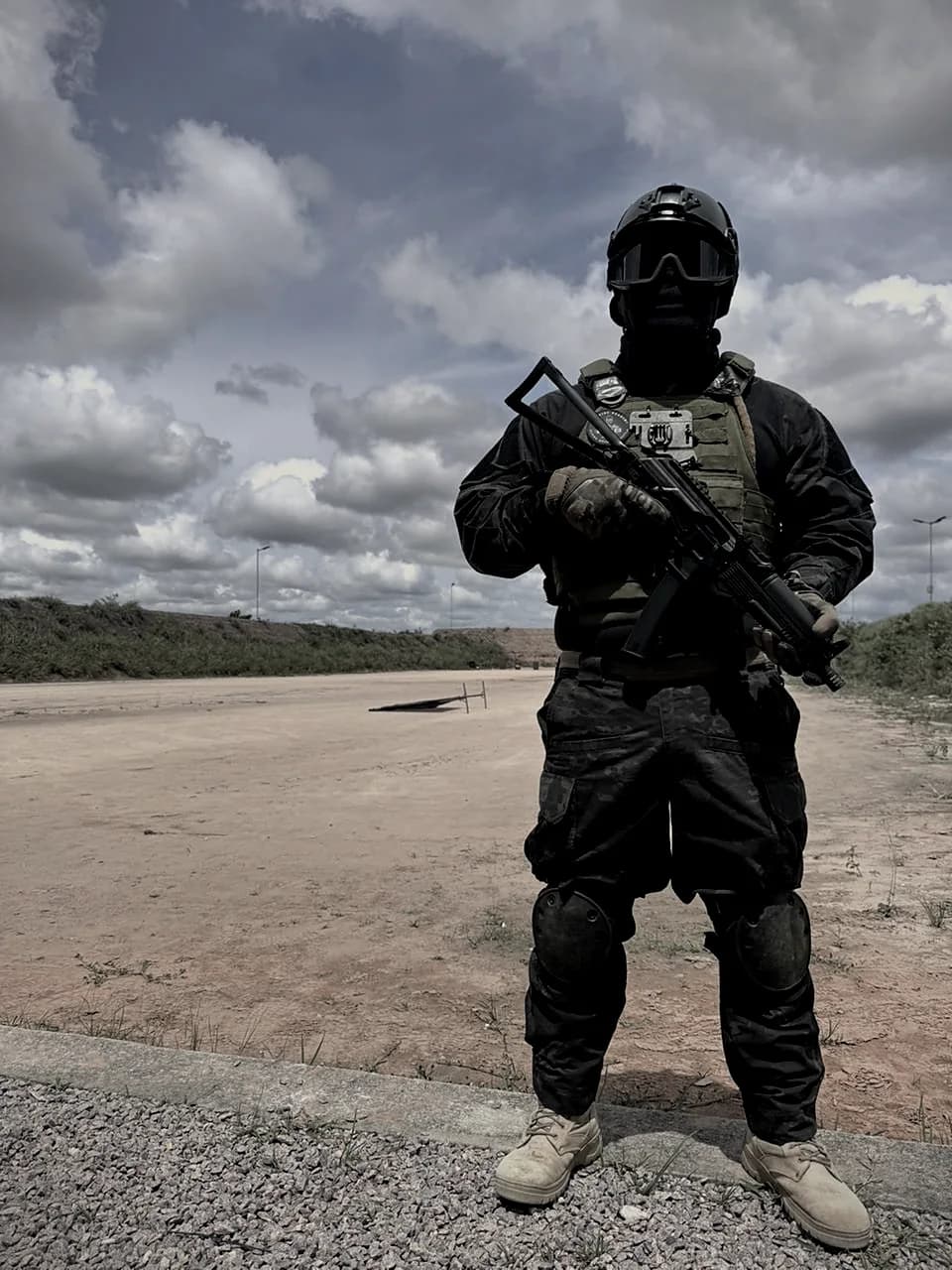 Atirador com equipamento tático completo e fuzil em posição de segurança, em estande de tiro ao ar livre